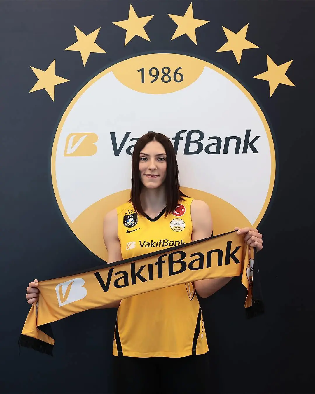 boscovic posa com uniforme amarelo diante de troféus após anúncio de transferência para novo clube.